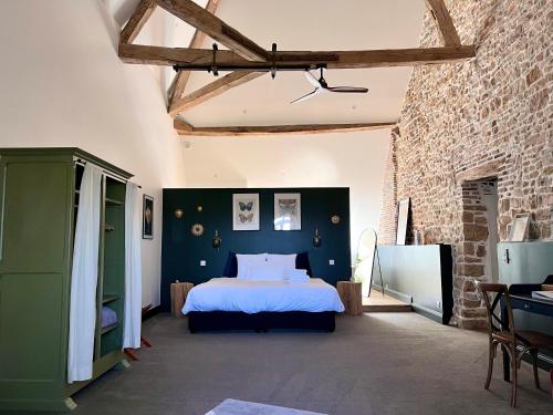 a bedroom with a bed and a brick wall at Les Chambres du parc in Monnières