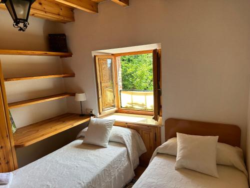 a bedroom with two beds and a window at Casa rural C de Caballo, Valdorria Brother Law SL in Valdorria