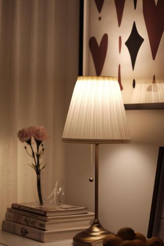 a lamp on a table with a vase and a flower at Collins Paris End suite- 2 bedrooms with balcony in Melbourne