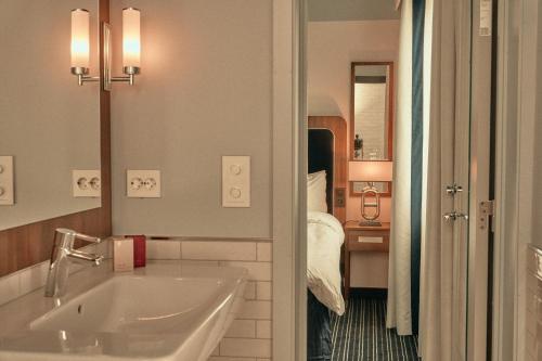 a bathroom with a sink and a bed in a room at Hotel Klubben in Tønsberg