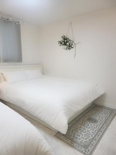 a white bed in a white bedroom with a plant on it at Have Stay in Gumi