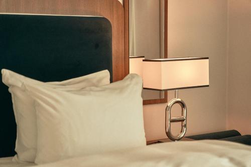 a bed with a white pillow and a lamp at Hotel Klubben in Tønsberg