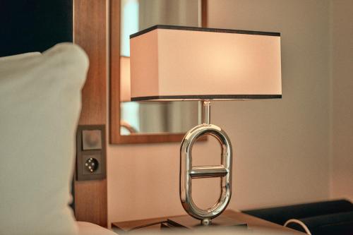a lamp sitting on a table next to a bed at Hotel Klubben in Tønsberg