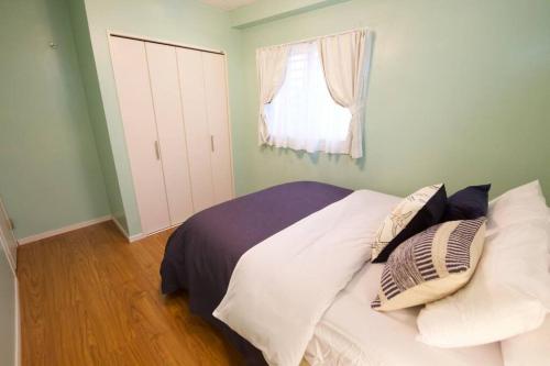 a bedroom with a bed with pillows and a window at YAMASHIRO House in Ginowan