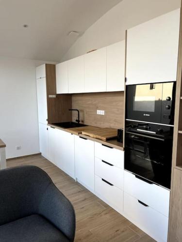 une cuisine avec des armoires blanches et un appareil noir dans l'établissement Maison en bord de mer, à Lumio