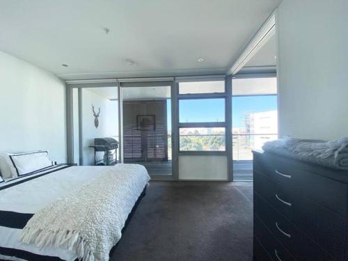a bedroom with a large bed and a large window at Modern Apartment With Pool and Gym in Napier