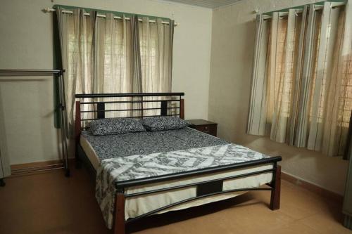 a bedroom with a bed in a room with windows at Coffee Camp Home Stay with Tree house in Kattappana