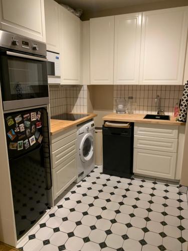 une cuisine avec des armoires blanches et un lave-vaisselle noir dans l'établissement Super Apartment, comfort design functional, à Paris