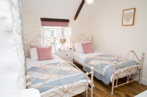 Habitación con 2 camas individuales y paredes blancas. en Derwen House Newport, Pembrokeshire, en Newport