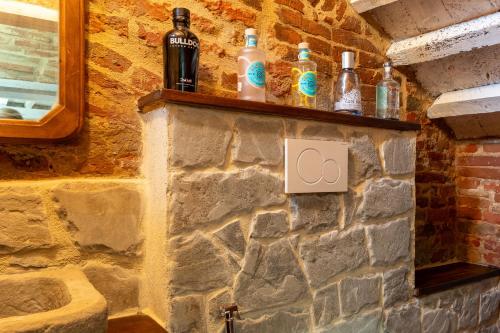 a stone wall with bottles on a shelf at La Casina in Foiano della Chiana