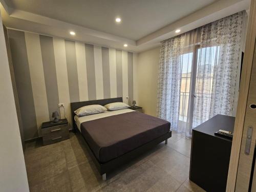 a bedroom with a bed and a large window at Flowers Apartments in Marineo