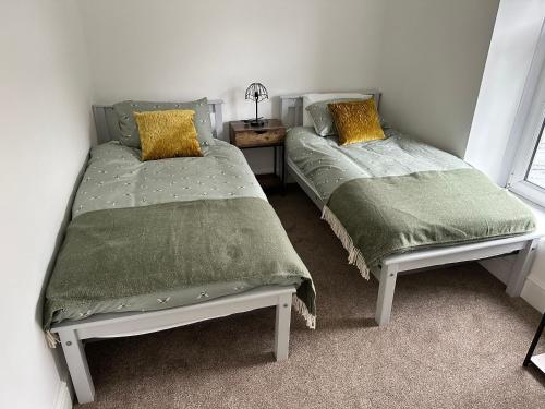 Dos camas una al lado de la otra en un dormitorio. en Stylish Miners Cottage, Treorchy, Rhondda, en Treorky