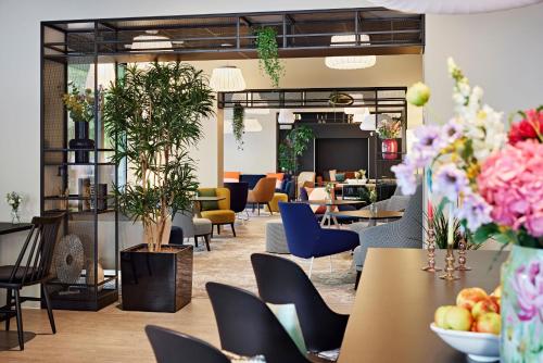 a lobby with tables and chairs and plants at LÉGÈRE EXPRESS Tuttlingen in Tuttlingen