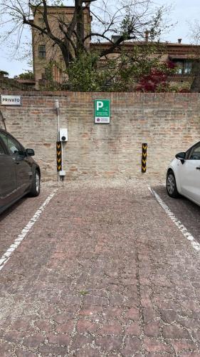 two cars parked in a parking lot next to a brick wall at Alkimia Smart Rooms in Ferrara