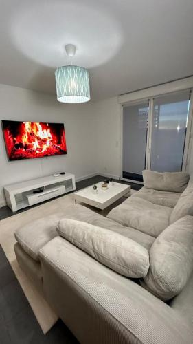 un salon avec un canapé et une télévision dans l'établissement Black Room: Votre Love Room près de Lyon, à Vénissieux