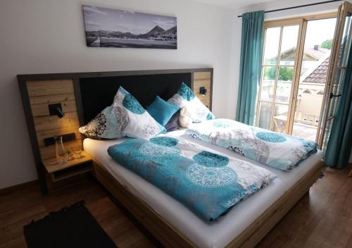 a bed with blue and white pillows and a window at Ferien by Wallners in Bad Feilnbach