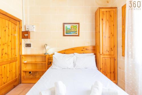 a bedroom with a white bed with a wooden headboard at Lovely Home with Private Terrace in Zebbug, Gozo by 360 Estates in Żebbuġ