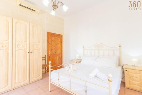 a bedroom with a white bed and a wooden closet at Lovely Home with Private Terrace in Zebbug, Gozo by 360 Estates in Żebbuġ