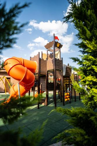 a playground with an orange slide in a park at Wellness Hotel Gyula in Gyula