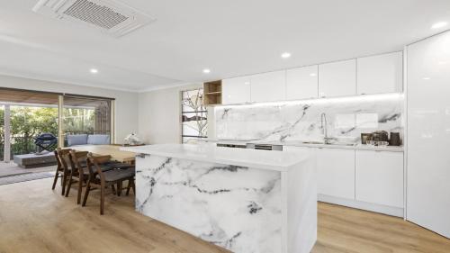 a kitchen with white marble countertops and a dining room at Azure - Luxe, Pool Beachfront in Kororo Basin