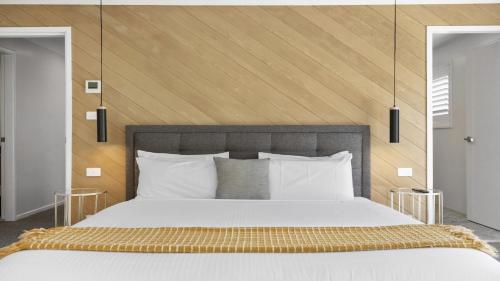 a bedroom with a large bed with a wooden headboard at Azure - Luxe, Pool Beachfront in Kororo Basin