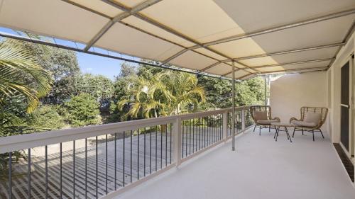 a balcony with two chairs and a table on it at Azure - Luxe, Pool Beachfront in Kororo Basin