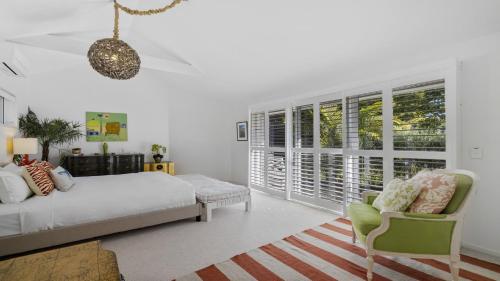 a bedroom with a bed and a chair and windows at Barellen Beach House - Luxe Beach Front, Oceanview in Woolgoolga
