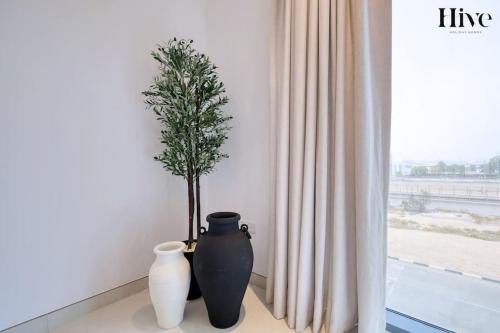 two vases and a tree in a room with a window at 7 By Aurora 101 in Dubai