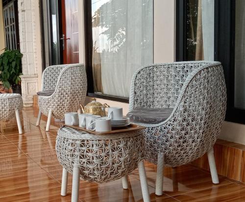 two chairs and a table with cups and mugs on it at Rezka Roomz Syari'ah in Ende