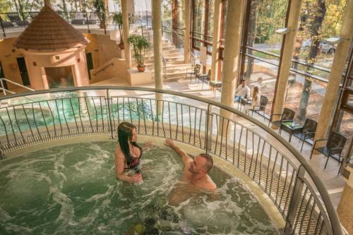 a man and woman in a hot tub at a resort at Wellness Hotel Gyula in Gyula