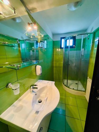 a green bathroom with a sink and a shower at Pensiunea Roua - Mountain View in Sinaia