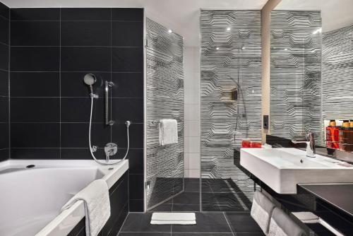 a bathroom with a tub and a sink at LÉGÈRE HOTEL Tuttlingen in Tuttlingen