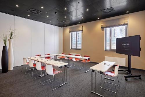 a conference room with tables and chairs and a screen at LÉGÈRE HOTEL Tuttlingen in Tuttlingen