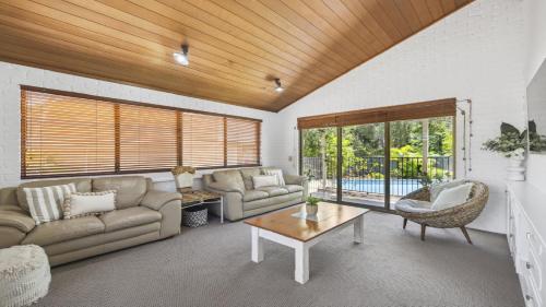 a living room with a couch and a table at Diggers Beach Surf House - Pool, Surf Beach, Pets, Sleeps 10 in Coffs Harbour