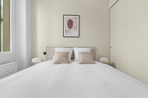 une chambre blanche avec un lit blanc avec deux oreillers dans l'établissement LB Vacation Rentals I Renovated Apartment Min from Beach and Palais, à Cannes