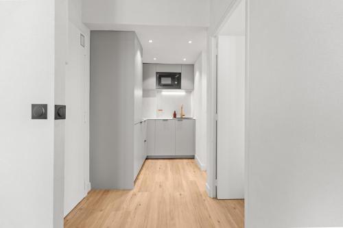 Il comprend une cuisine avec des murs blancs et du parquet. dans l'établissement LB Vacation Rentals I Renovated Apartment Min from Beach and Palais, à Cannes