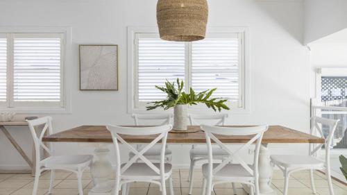 una sala da pranzo con un tavolo di legno e sedie bianche di Fairways Beach House - Pool, Golf, Sawtell Village, Family Friendly a Sawtell