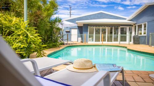 a hat sitting on a table next to a swimming pool at Fairways Beach House - Pool, Golf, Sawtell Village, Family Friendly in Sawtell