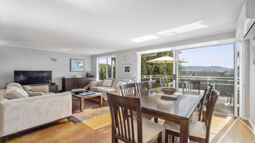 a living room with a table and a couch at Jetty Hideaway - Cosy Cottage, Fireplace, Gardens in Coffs Harbour