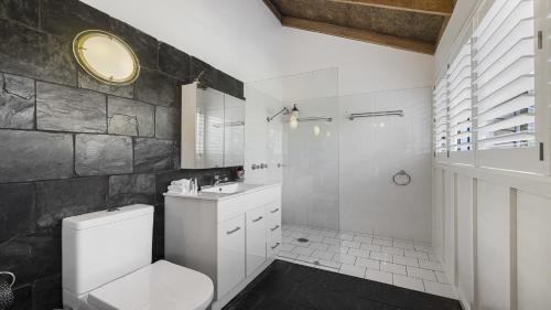 a bathroom with a white toilet and a sink at Jetty Hideaway - Cosy Cottage, Fireplace, Gardens in Coffs Harbour