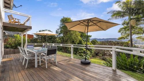a wooden deck with a table and an umbrella at Jetty Hideaway - Cosy Cottage, Fireplace, Gardens in Coffs Harbour