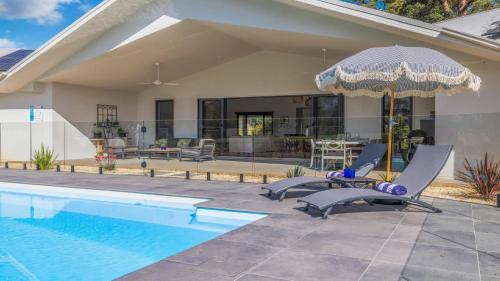 a house with a swimming pool with two chairs and an umbrella at Koala Lane - Family, Pool, Sleeps 10, Luxe in Bonville