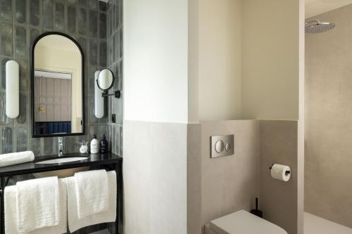 a bathroom with a sink and a toilet and a mirror at Hotel Grand Coeur Latin in Paris