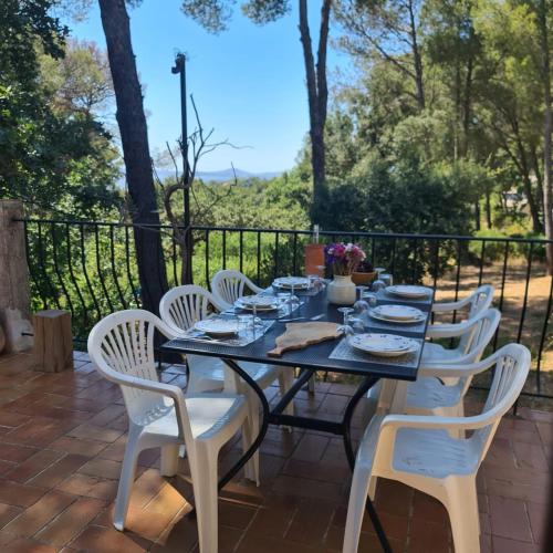 une table noire avec des chaises blanches sur une terrasse dans l'établissement Maison de Campagne proche plage, au Pradet