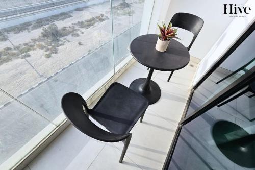 two chairs and a table in a room with a window at 7 By Aurora 301 in Dubai
