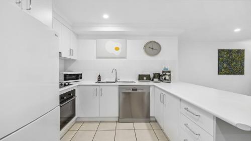 a white kitchen with white cabinets and a sink at Lindy Lou's - Village at Doorstep, Restaurants in Sawtell