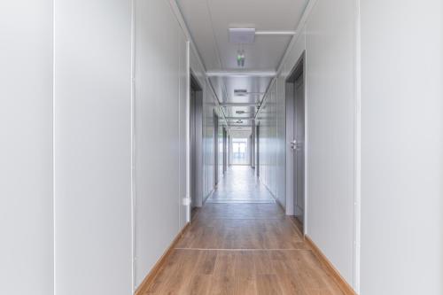 an empty corridor in an office building with white walls and wooden floors at TASKAN Noclegi in Okmiany