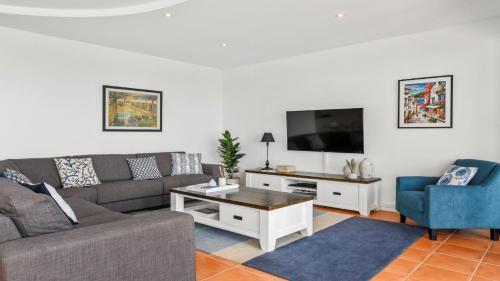 a living room with a couch and a tv at Villa Provence - Stunning Views, Walk to resorts. 5 Bed 3 Bath in Coffs Harbour