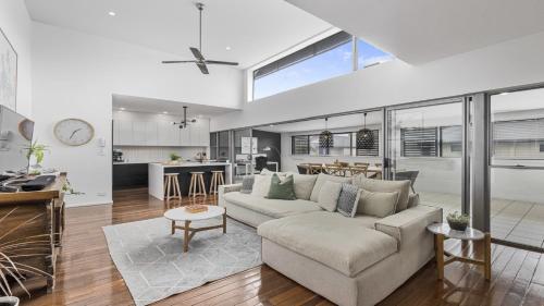 a living room with a couch and a kitchen at Luxe Jetty Apartment - Stylish, Walk to Beach & Cafes in Coffs Harbour