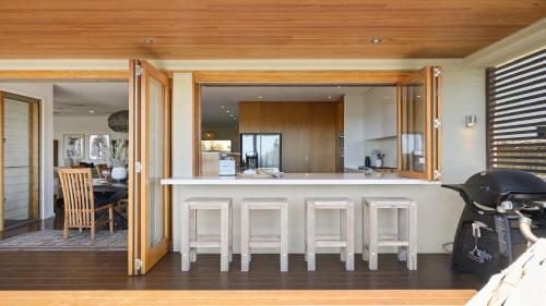 a kitchen and living room with a bar with stools at Sundecks - Stunning Oceanview Beach House in Emerald Beach in Emerald Beach